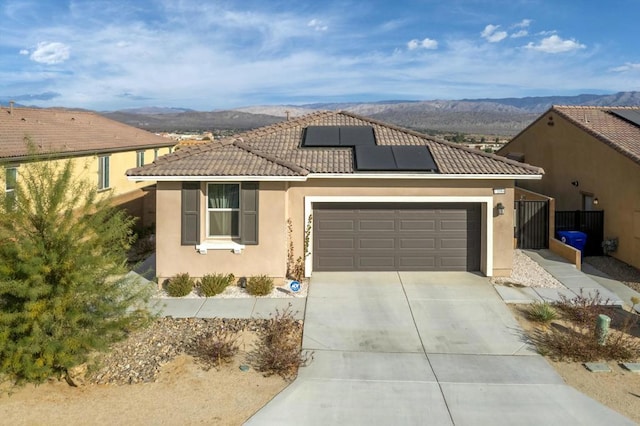 view of front of house featuring solar panels, a mountain view, and a garage