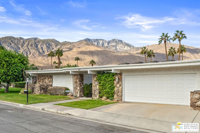 ranch-style home with a mountain view, a front yard, and a garage