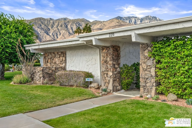 view of exterior entry featuring a mountain view and a yard