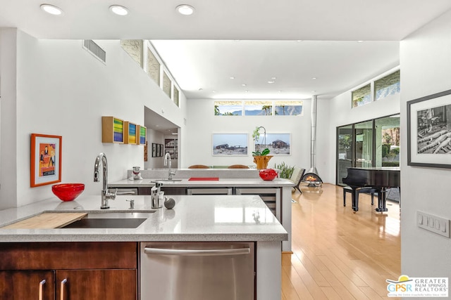 kitchen with light wood-type flooring, stainless steel dishwasher, and sink