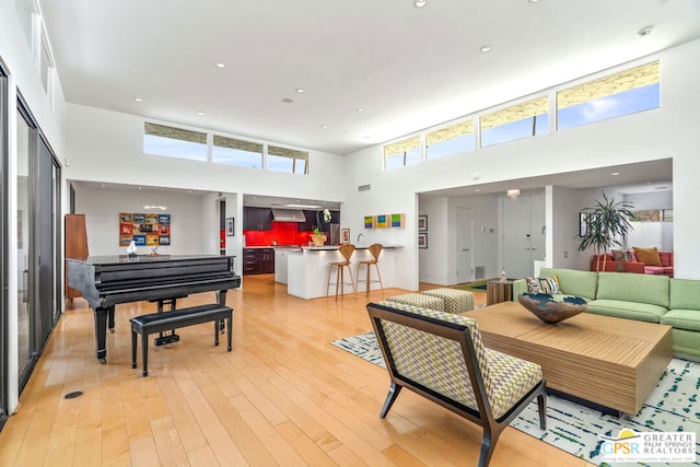 living room featuring a towering ceiling and light wood-type flooring