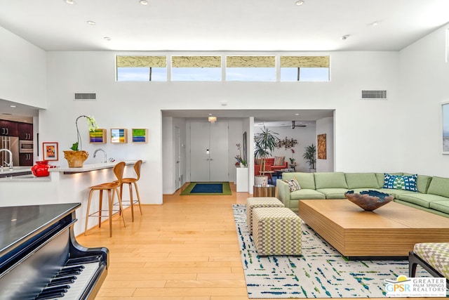 living room featuring light wood-type flooring, a towering ceiling, and a wealth of natural light