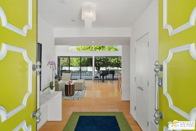 hall with wood-type flooring and an inviting chandelier