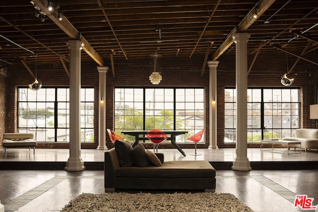 unfurnished sunroom featuring decorative columns and lofted ceiling with beams