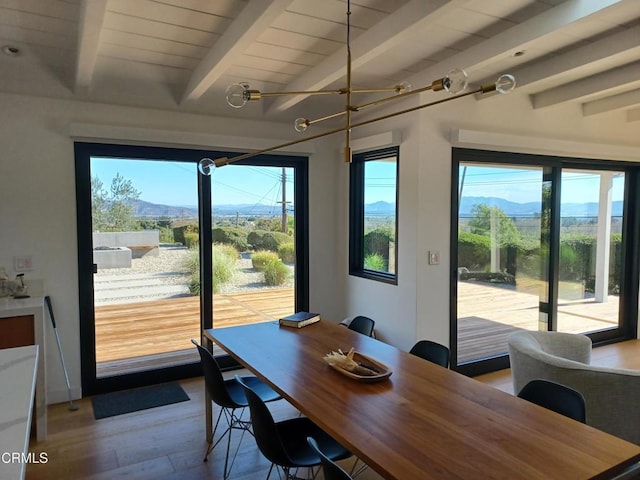 dining space featuring a mountain view, beam ceiling, and plenty of natural light