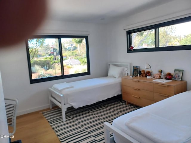 bedroom with hardwood / wood-style flooring and multiple windows