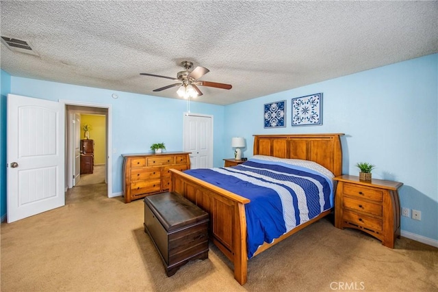 bedroom featuring ceiling fan, a closet, light carpet, and a textured ceiling