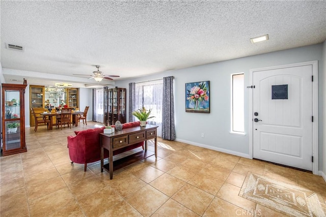 living room with ceiling fan, light tile patterned floors, and a textured ceiling