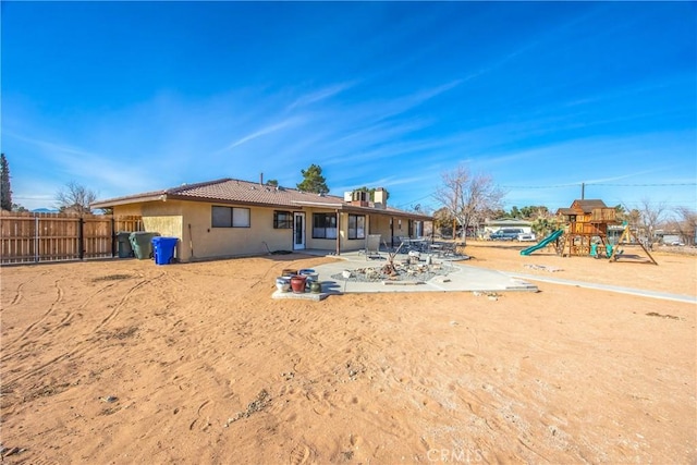 rear view of property with a playground and a patio