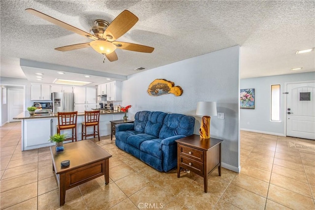 tiled living room with ceiling fan and a textured ceiling