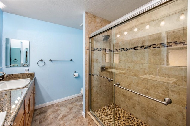 bathroom with vanity, an enclosed shower, a textured ceiling, and toilet