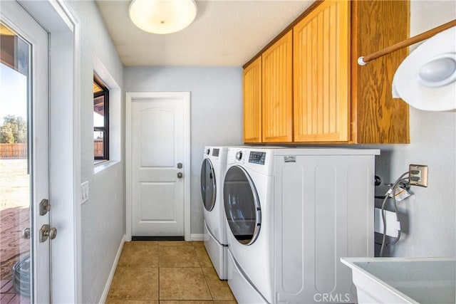 clothes washing area featuring independent washer and dryer, cabinets, sink, and light tile patterned floors