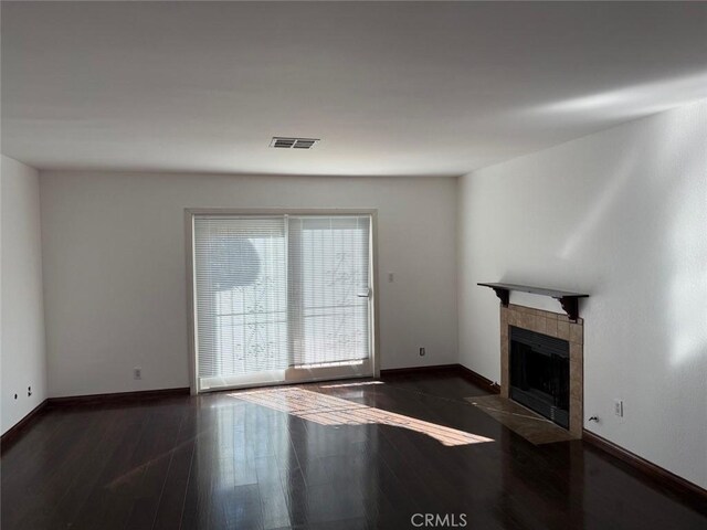 unfurnished living room with dark wood-type flooring and a tile fireplace