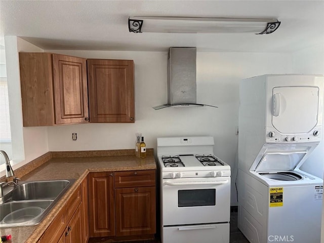 kitchen featuring stacked washer and clothes dryer, white range with gas cooktop, sink, and wall chimney exhaust hood