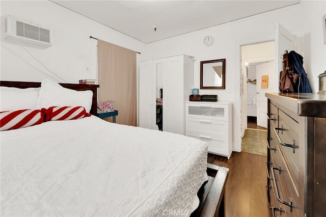 bedroom with dark wood-type flooring, a closet, and a wall mounted AC