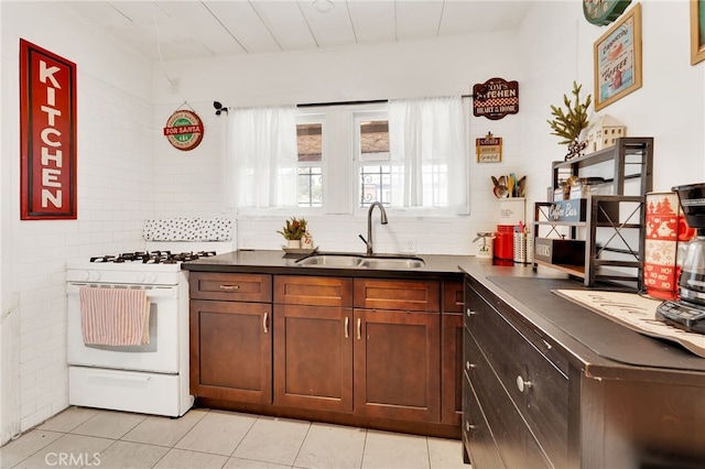 kitchen featuring light tile patterned flooring, white range with gas cooktop, sink, and decorative backsplash