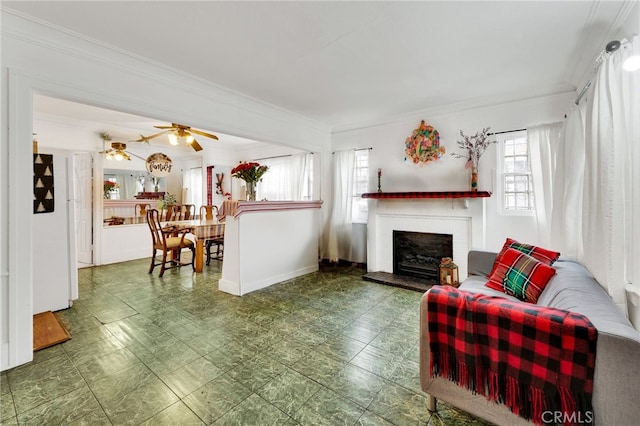 living room with ceiling fan, ornamental molding, and a fireplace