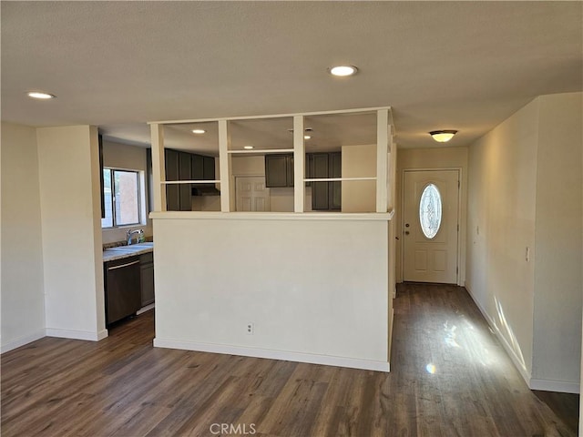 kitchen featuring sink, dark wood-type flooring, stainless steel dishwasher, and dark brown cabinets