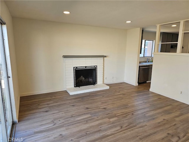 unfurnished living room featuring sink, a fireplace, and hardwood / wood-style floors