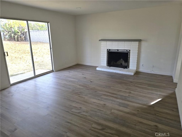 unfurnished living room with a brick fireplace and dark hardwood / wood-style floors