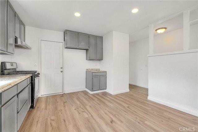 kitchen featuring gas range, gray cabinets, and light wood-style flooring