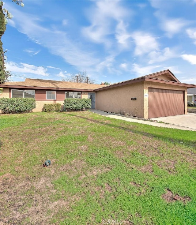 ranch-style home featuring a front yard, an attached garage, driveway, and stucco siding