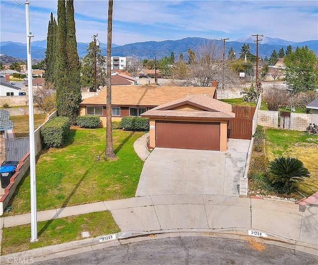 ranch-style home featuring a mountain view, driveway, a front yard, and fence