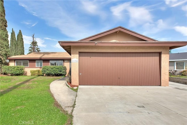 view of front of house featuring stucco siding, a garage, concrete driveway, and a front lawn