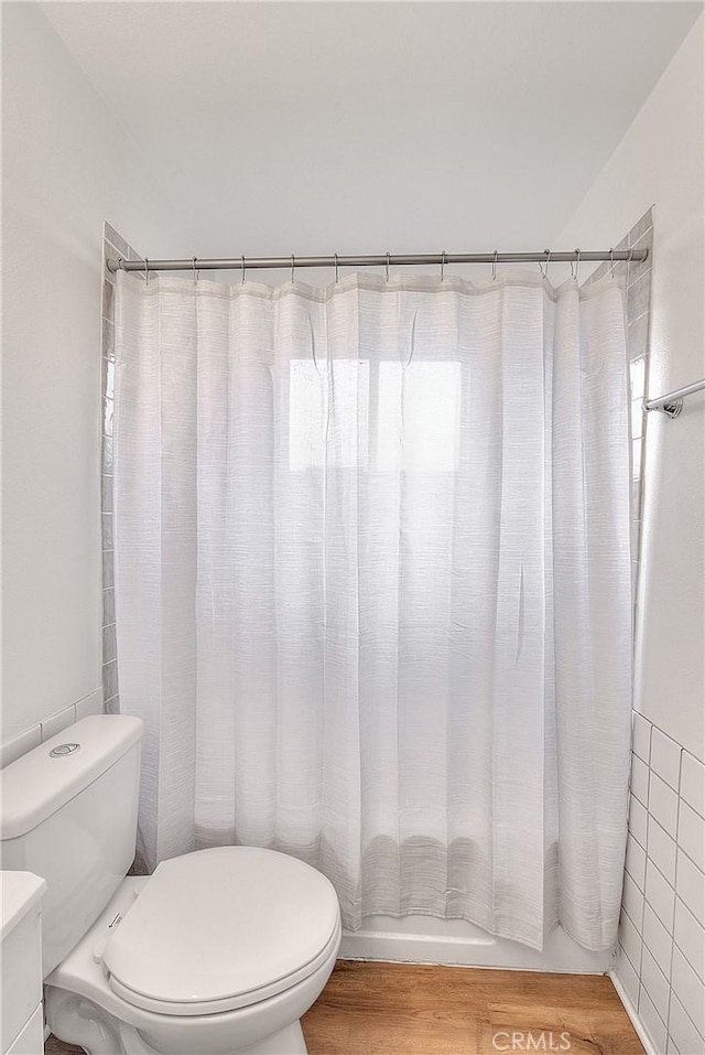 bathroom featuring shower / tub combo, toilet, and wood finished floors