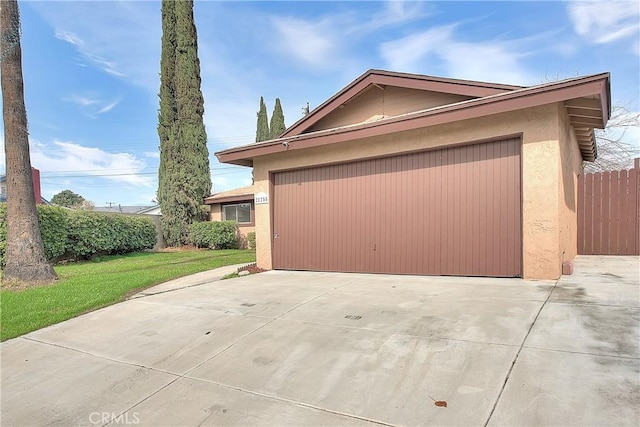 view of home's exterior with fence, driveway, stucco siding, a garage, and a lawn