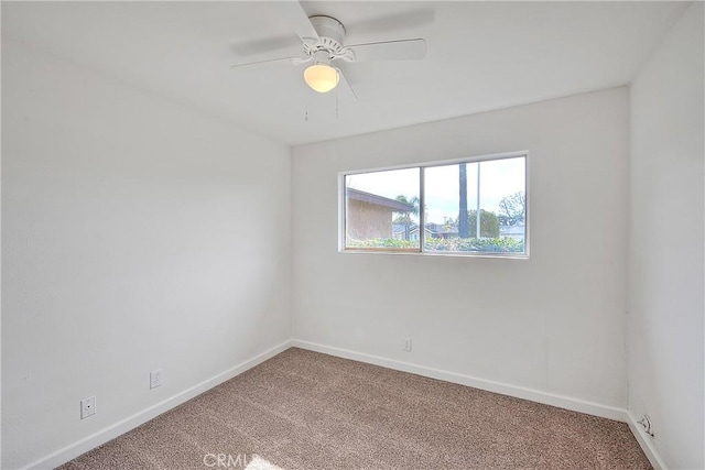 carpeted spare room featuring a ceiling fan and baseboards