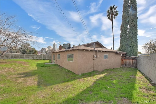 view of home's exterior featuring stucco siding, a lawn, and a fenced backyard