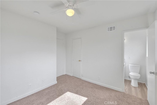 unfurnished bedroom with visible vents, connected bathroom, a ceiling fan, and baseboards