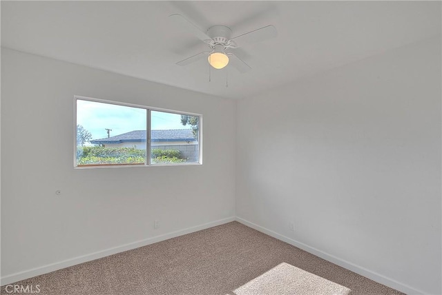 carpeted spare room featuring a ceiling fan and baseboards