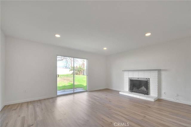 unfurnished living room featuring recessed lighting, a fireplace, baseboards, and wood finished floors