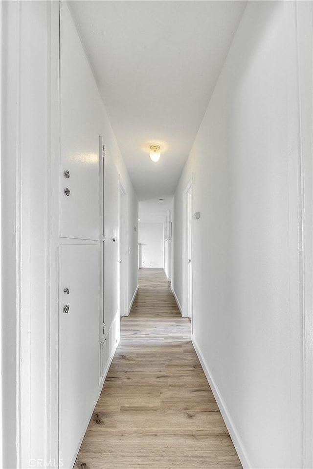 hall featuring light wood-style flooring and baseboards