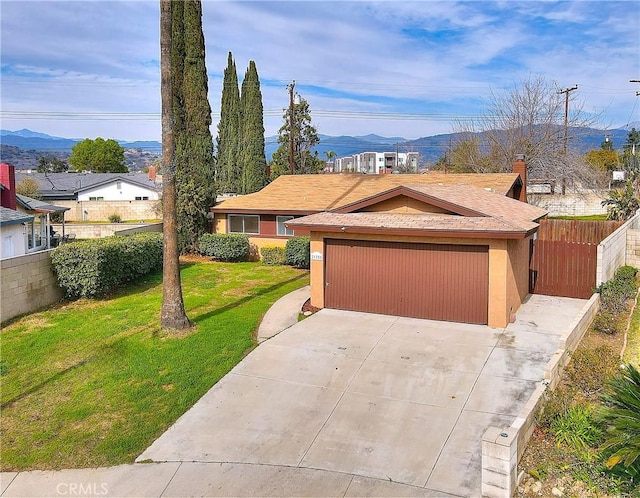 view of front of property featuring fence, concrete driveway, a front yard, stucco siding, and a garage