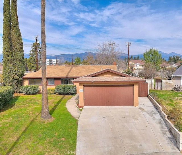 single story home featuring fence, a front yard, driveway, a garage, and a mountain view