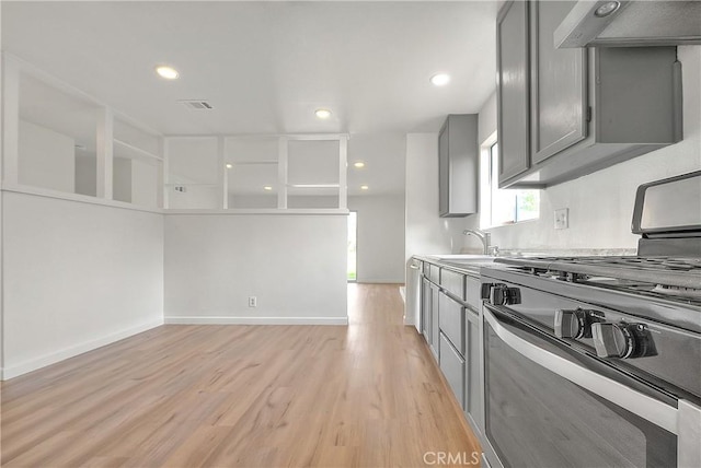 kitchen featuring visible vents, gray cabinets, range hood, light wood-style floors, and gas range