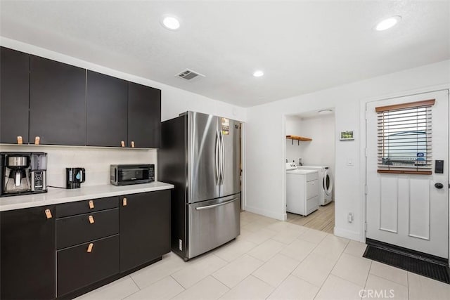 kitchen featuring stainless steel fridge, separate washer and dryer, and light tile patterned floors