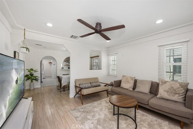 living room featuring light hardwood / wood-style floors, ceiling fan, and crown molding