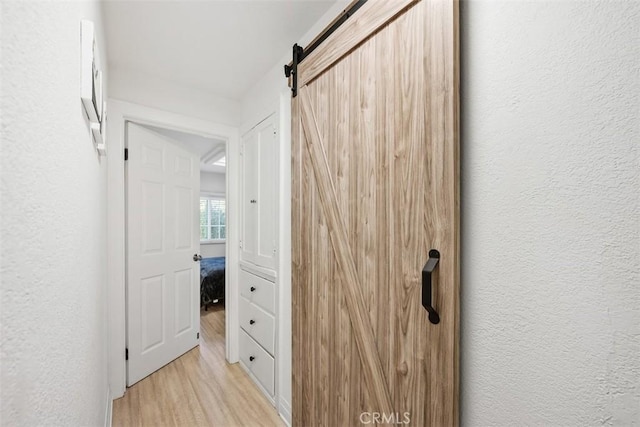 hall with a barn door and light wood-type flooring