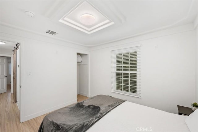 bedroom with a barn door, a closet, and light wood-type flooring