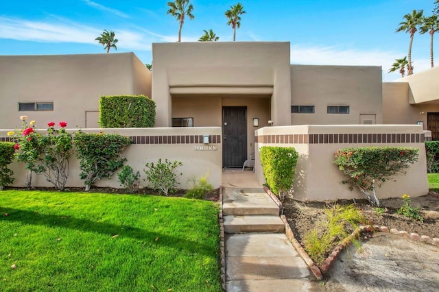 pueblo-style home with a front lawn