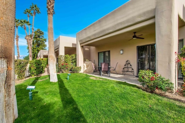 rear view of property featuring ceiling fan, a yard, and a patio