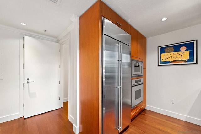 kitchen featuring built in appliances and light hardwood / wood-style floors