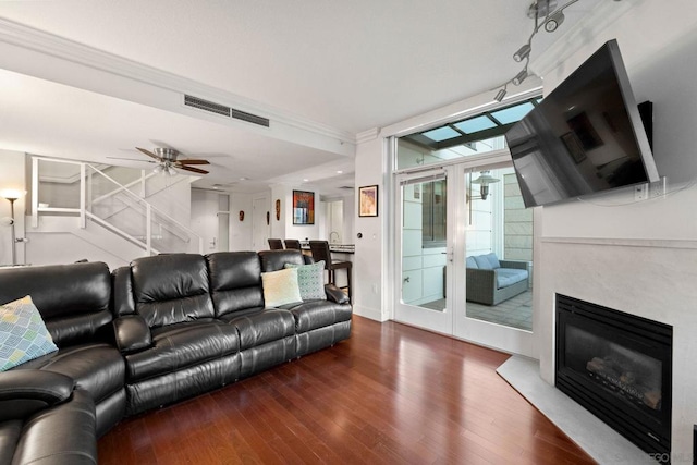 living room featuring wood-type flooring, ceiling fan, and ornamental molding