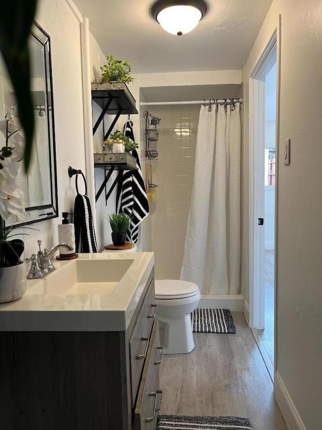 bathroom featuring toilet, a shower with curtain, hardwood / wood-style floors, and vanity