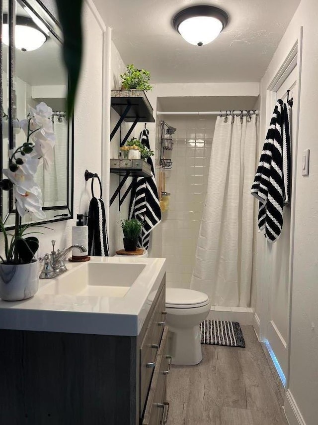 bathroom featuring toilet, vanity, wood-type flooring, and curtained shower