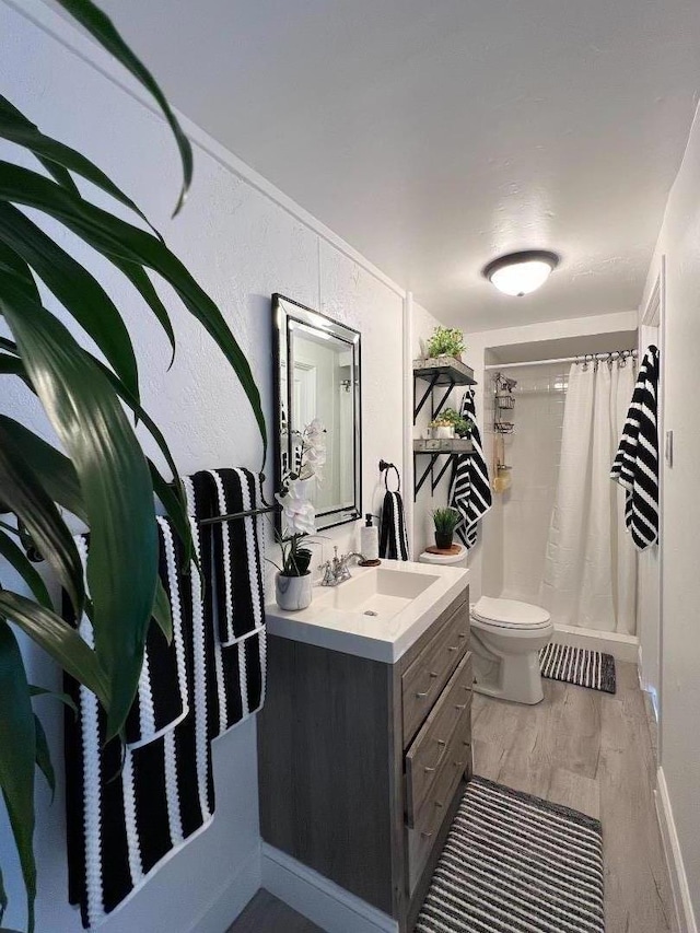 bathroom with vanity, toilet, hardwood / wood-style floors, and walk in shower